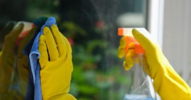Mains d'une personne avec des gants jaunes qui nettoient une vitre