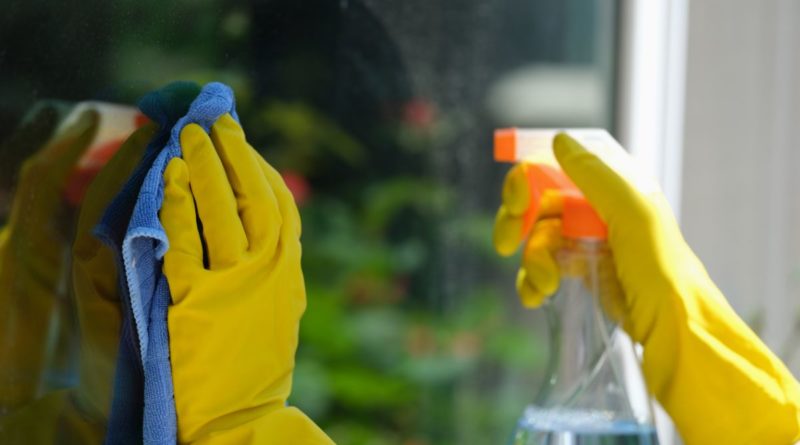 Mains d'une personne avec des gants jaunes qui nettoient une vitre